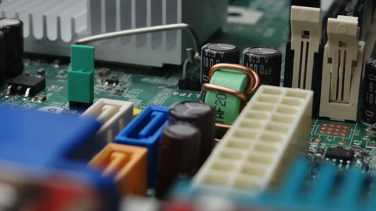 A close-up view of a computer motherboard, featuring various components such as capacitors, resistors, and integrated circuits.